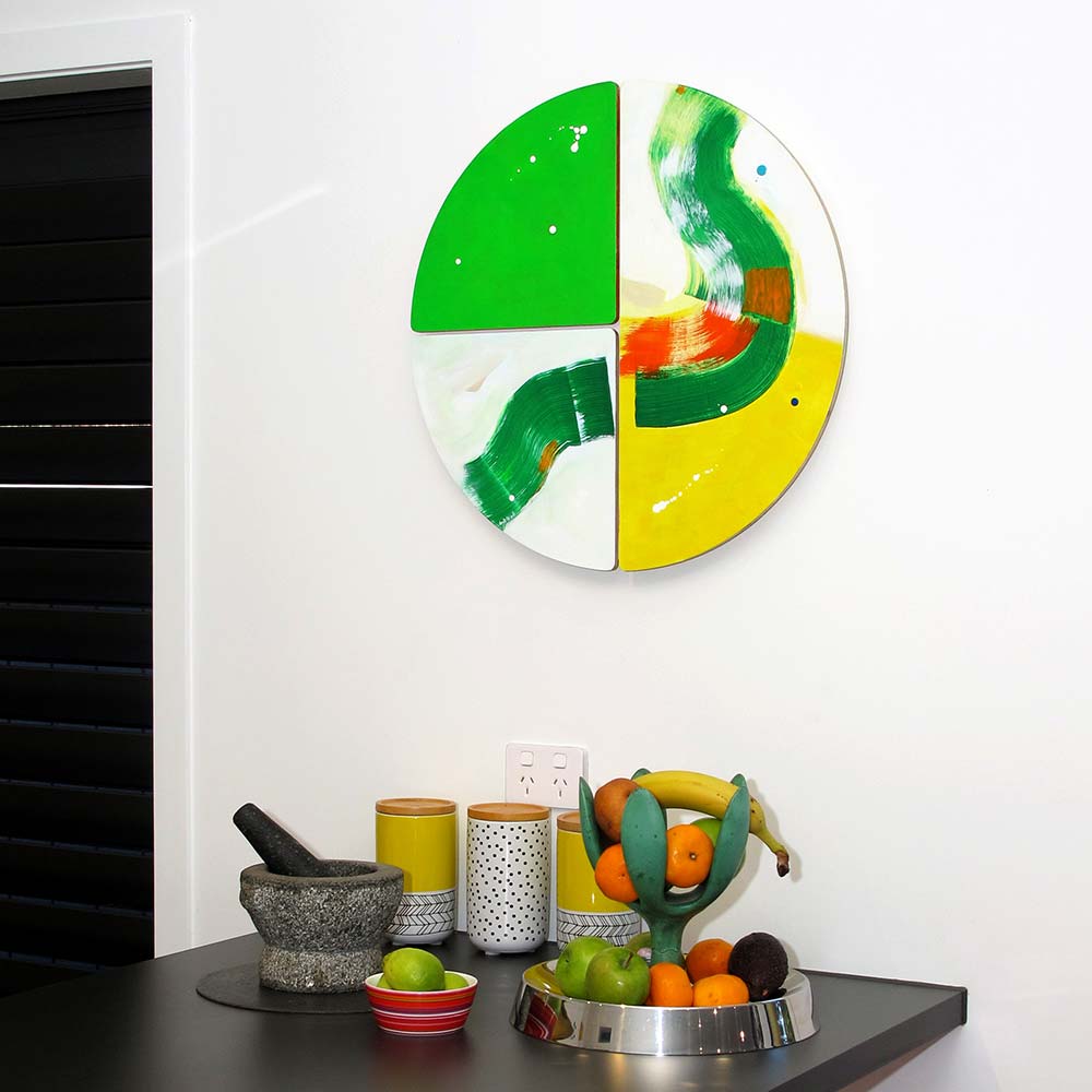 Crocodile Belly Skid wall sculpture by Kirsty Black with its vivid green and yellow forms catching the light above a dark kitchen bench with fruit bowl and canisters in a contemporary New Zealand interior.