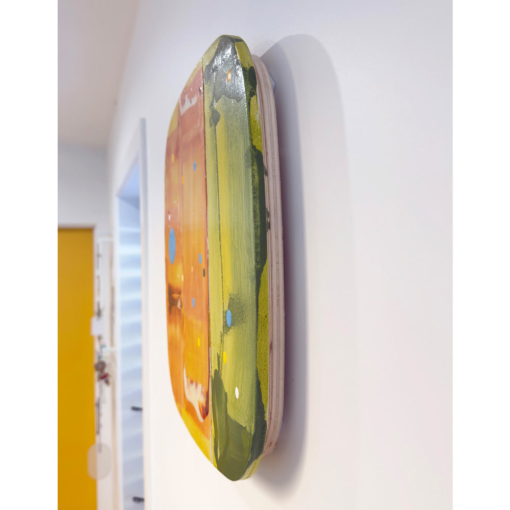Side-angle view of Bosc, a shaped acrylic-on-ply panel painting from the Sorbet Series, showing its curved edge and layered orange and olive-green paint, hung on a white wall.