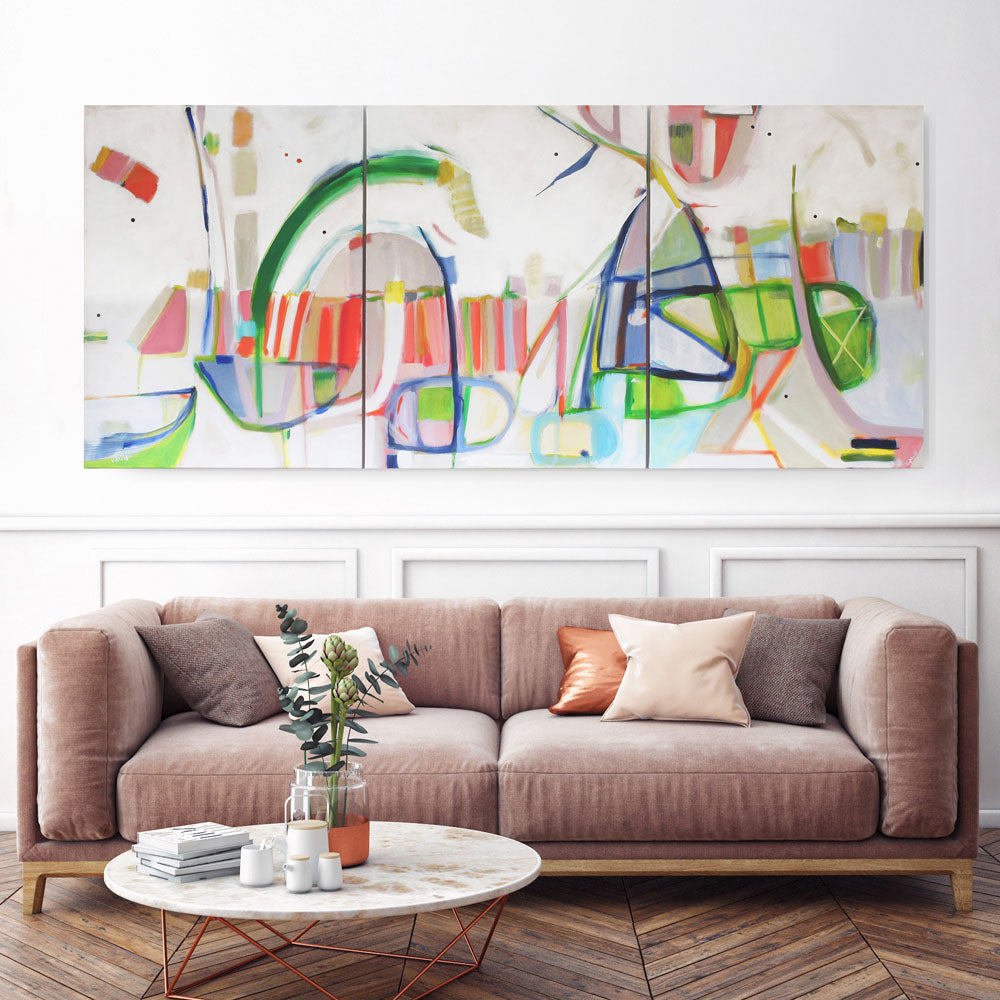Chameleon Rollercoaster triptych by Kirsty Black hung above tan sofa showing three connected panels with flowing green blue coral and yellow forms