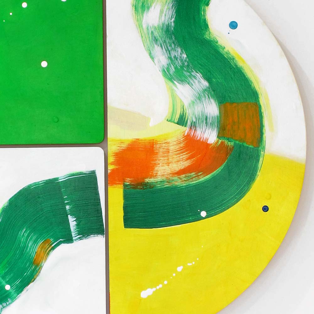 Detail of Crocodile Belly Skid wall sculpture by Kirsty Black showing fluid forest green brushwork curving across sunny yellow with an orange accent, blue dot detail and white paint splatter across adjoining bevelled plywood tiles.