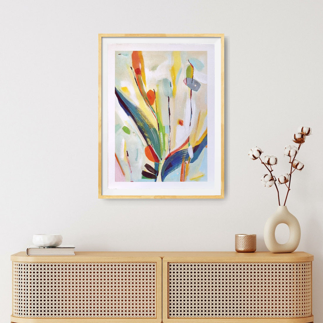 Framed abstract painting on a light coloured wall above a dresser