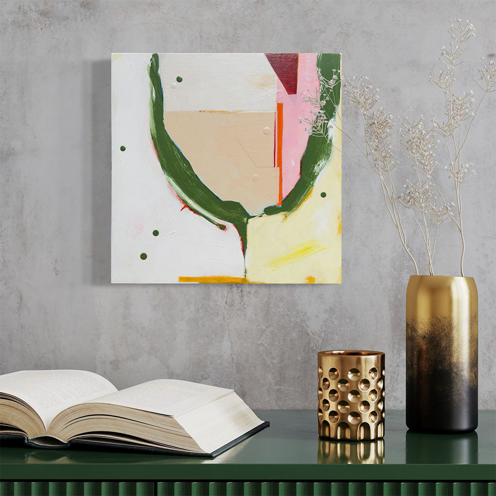 Pixie Bunker abstract painting by Kirsty Black on concrete wall above dark green desk with open book, gold perforated candle holder, gold cylindrical vase and dried white flower stems