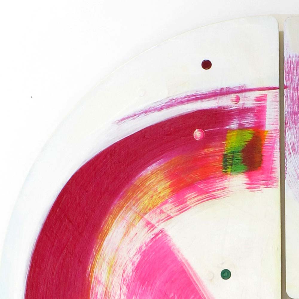 Close-up of Roller Disco Dames wall sculpture by Kirsty Black showing sweeping magenta and pink arcs on white with a small green and yellow accent block and scattered dot details across adjoining bevelled plywood tiles.