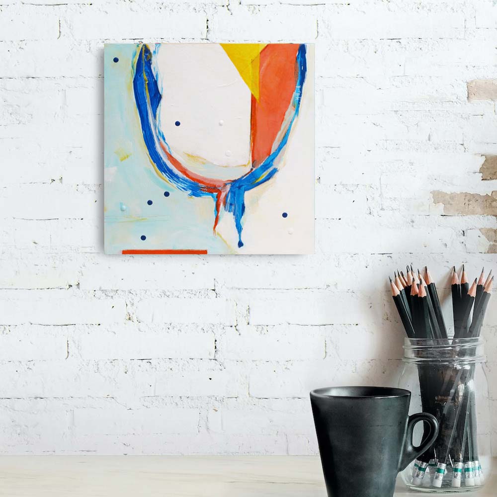Leprechaun Condo original abstract painting by Kirsty Black hung on white brick wall above timber desk with pencils and mug, showing scale of 300x300mm ply box board