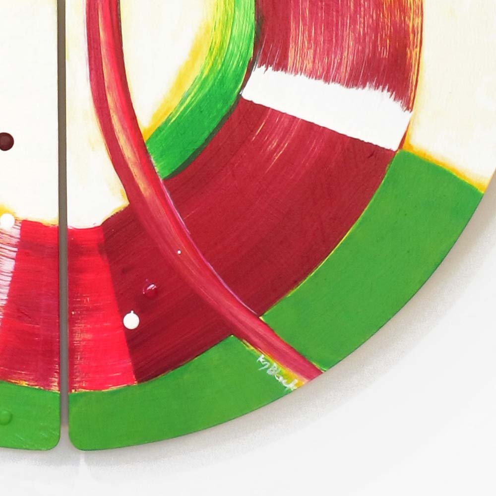 Detail of Sausage Dog Wheelie wall sculpture by Kirsty Black showing layered crimson and deep red arcs meeting vivid green across adjoining bevelled plywood tiles with artist signature visible.