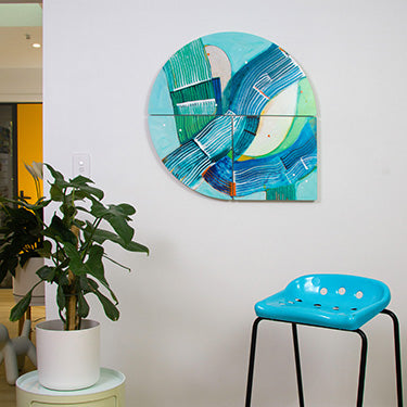 Abstract wall art piece with a plant and blue chair in a room setting