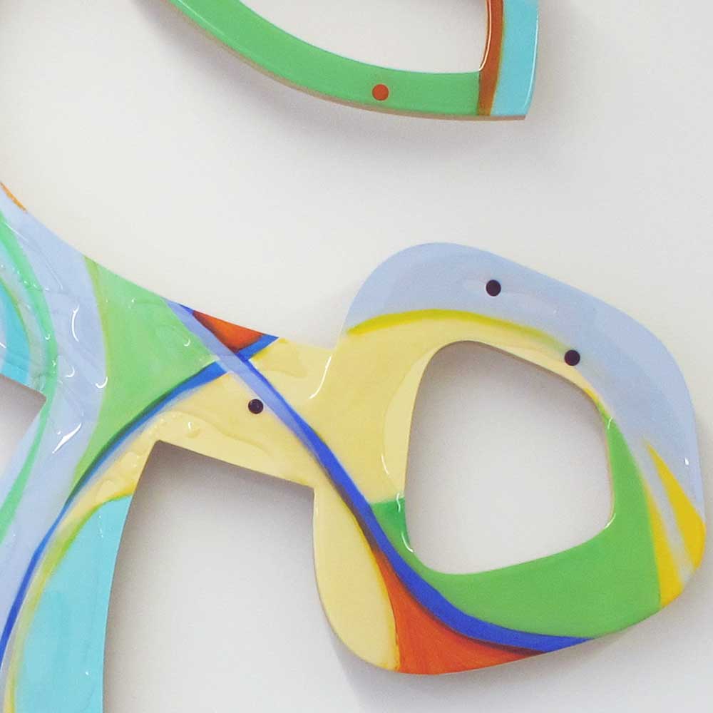 Detail of Cartwheeling Crustacean wall sculpture by Kirsty Black showing interlocking curved forms in yellow, green and pale blue with cobalt blue linear accent and navy dot details and resin pour.