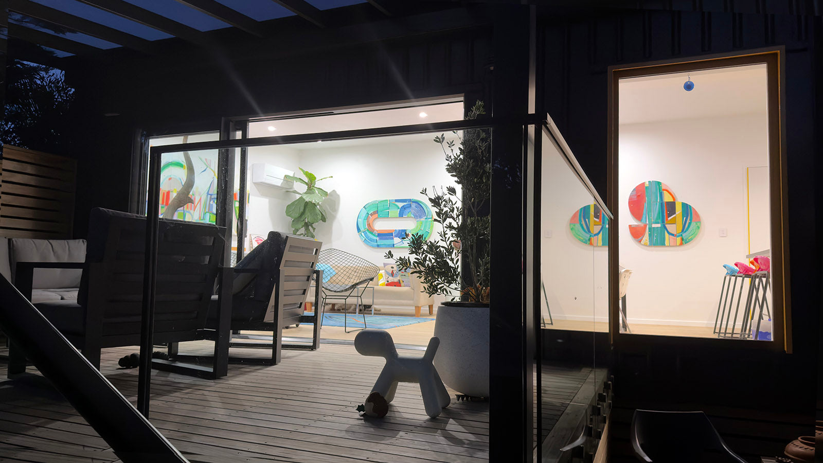 Contemporary abstract art collection by Kirsty Black displayed in modern New Zealand home interior at evening, featuring colorful geometric paintings