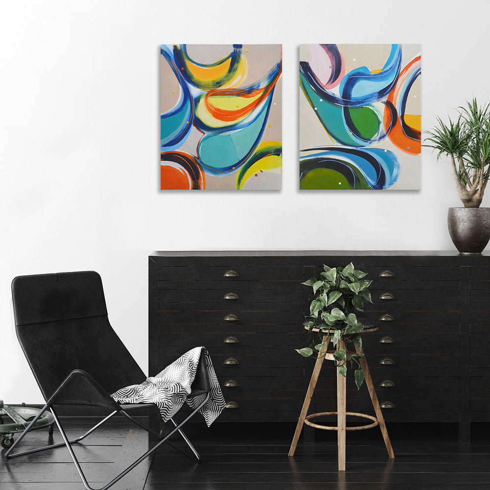 Gossip Guys and Gas Bag Gals abstract paintings by Kirsty Black hung as a pair on white wall above black flat file cabinet with leather chair and trailing ivy plant