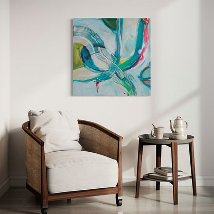 Original abstract painting in aqua, teal and green tones displayed above a rattan armchair with white cushion in a sun-drenched minimalist room