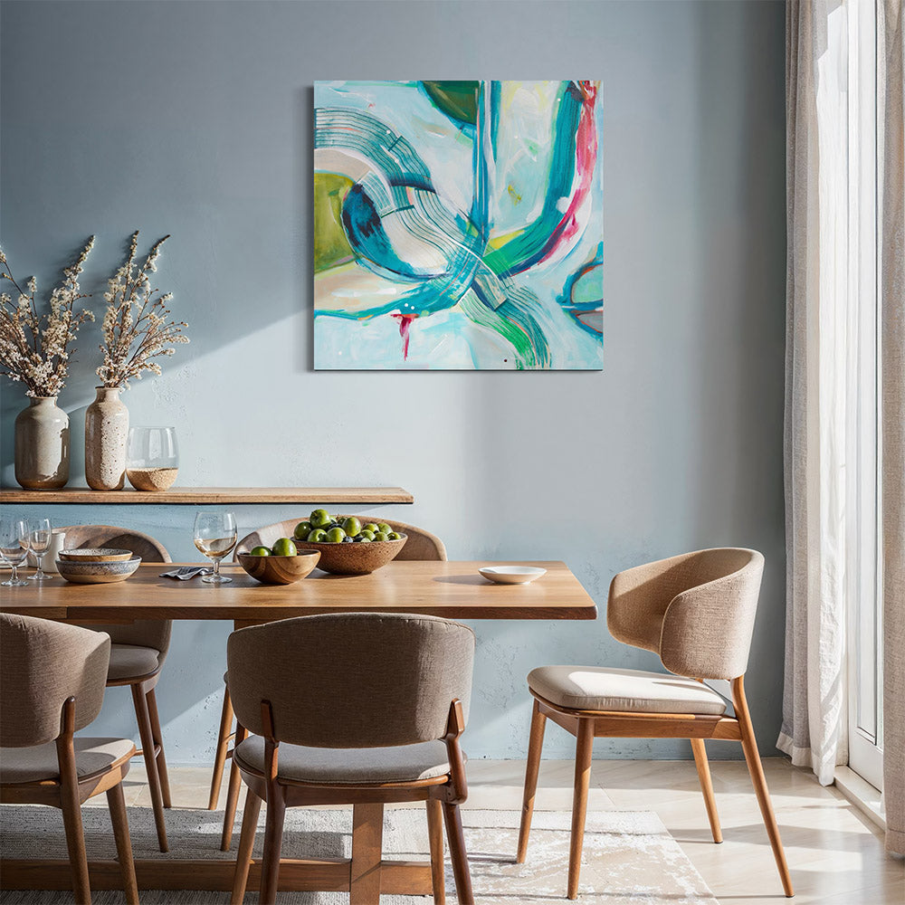 Abstract painting in teal, green and pink hanging above a timber dining table with linen chairs, styled with dried flowers and green apples against a blue-grey wall