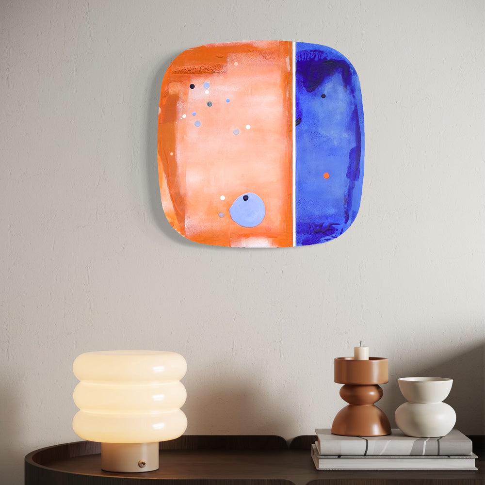 Kumquat Sorbet, original abstract painting by Kirsty Black shown in situ above a cabinet with a lamp and decorative objects, illustrating scale and how the bevelled plywood sits proud of the wall.