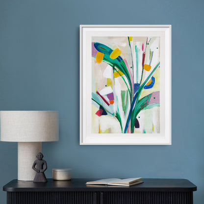 Joyful abstract artwork on paper in a  float mounted with a white frame hanging on a blue wall