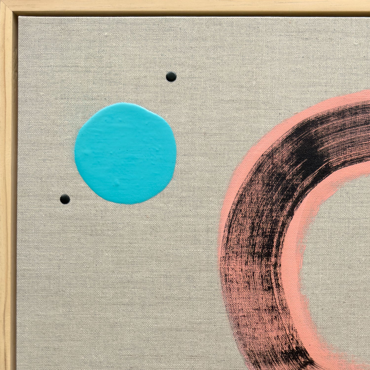Close-up detail of Pussy Cat Prowl showing the vivid turquoise circle with scattered black dots and the edge of the pink sweeping arc on cool grey linen ground in natural wood tray frame