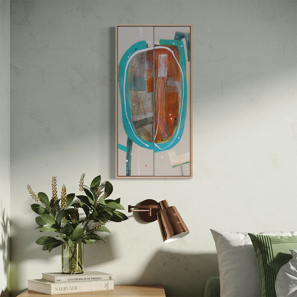 Racetrack Rumble framed abstract diptych by Kirsty Black hung on soft green textured wall in bedroom setting with copper wall sconce, glass vase of greenery and stacked art books