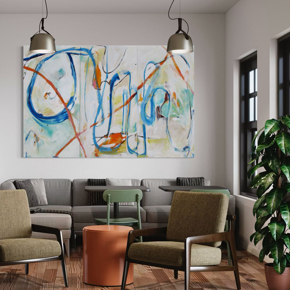 Tentacled Tantrum triptych painting by Kirsty Black displayed on white wall above modern living room seating area showing the full scale of the three-panel composition with flowing blue and orange forms